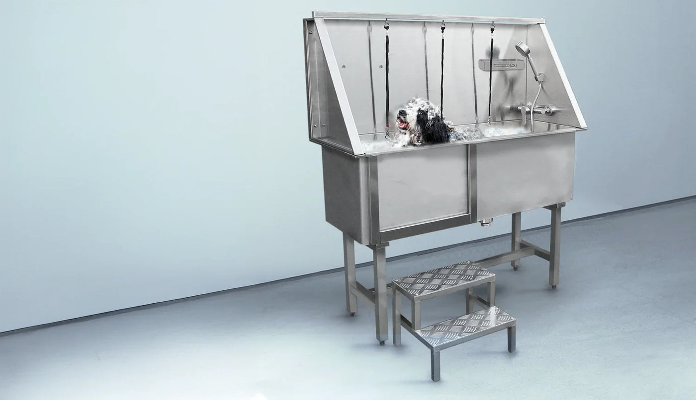 Stainless steel dog grooming tub with a textured surface, featuring a showerhead and steps for easy access, set against a light background