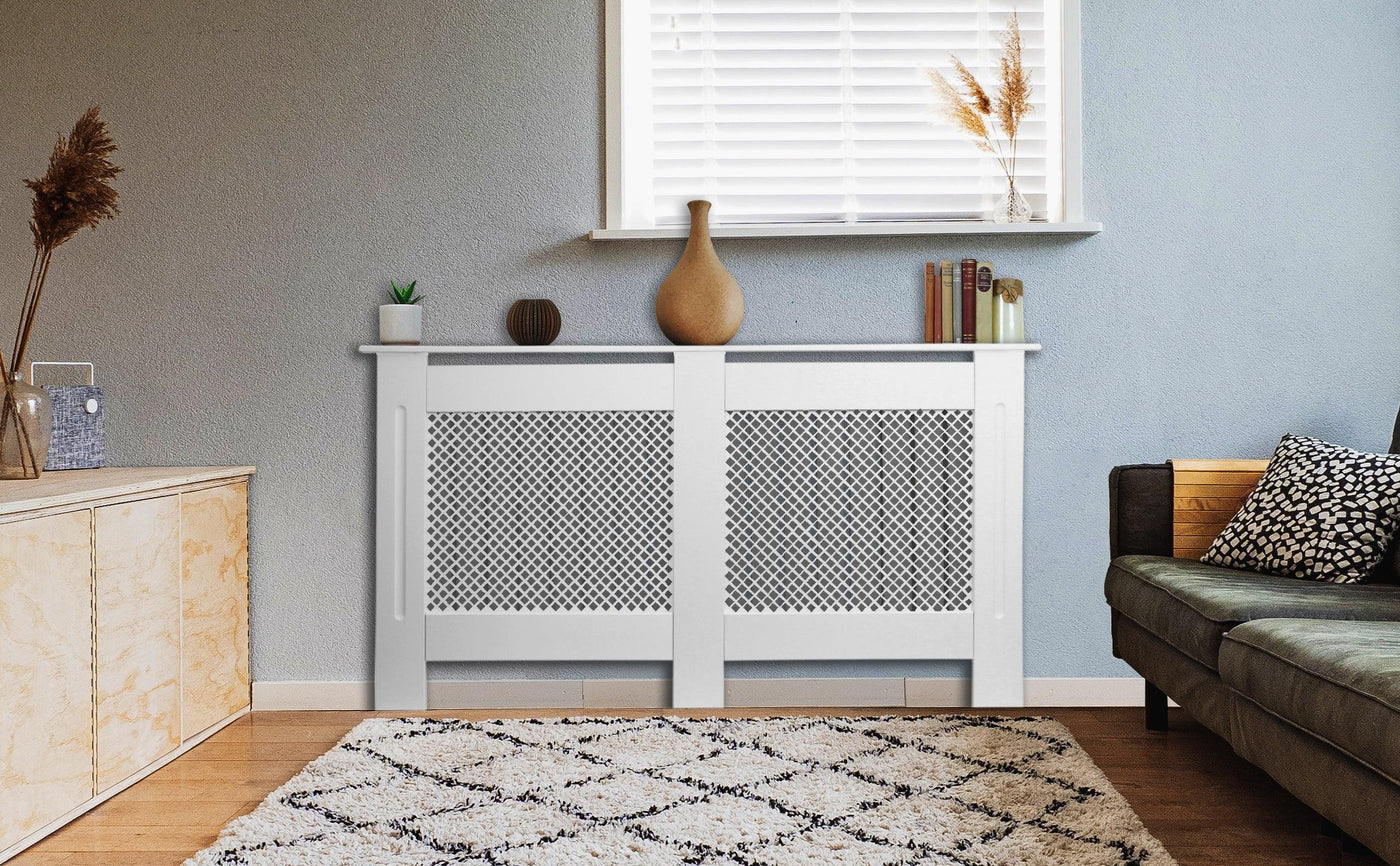 Modern living room featuring a white radiator cover with a geometric pattern, a vase, books, and a cozy sofa on a textured rug
