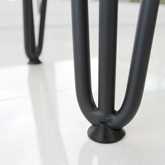 Close-up of sleek black metal table legs with a smooth finish, resting on a glossy white tiled floor, highlighting modern design