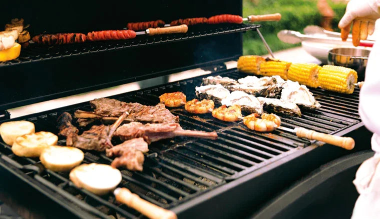 Grilled meats, shrimp, and oysters on a barbecue, with vibrant corn and colorful vegetables, creating a mouthwatering summer feast