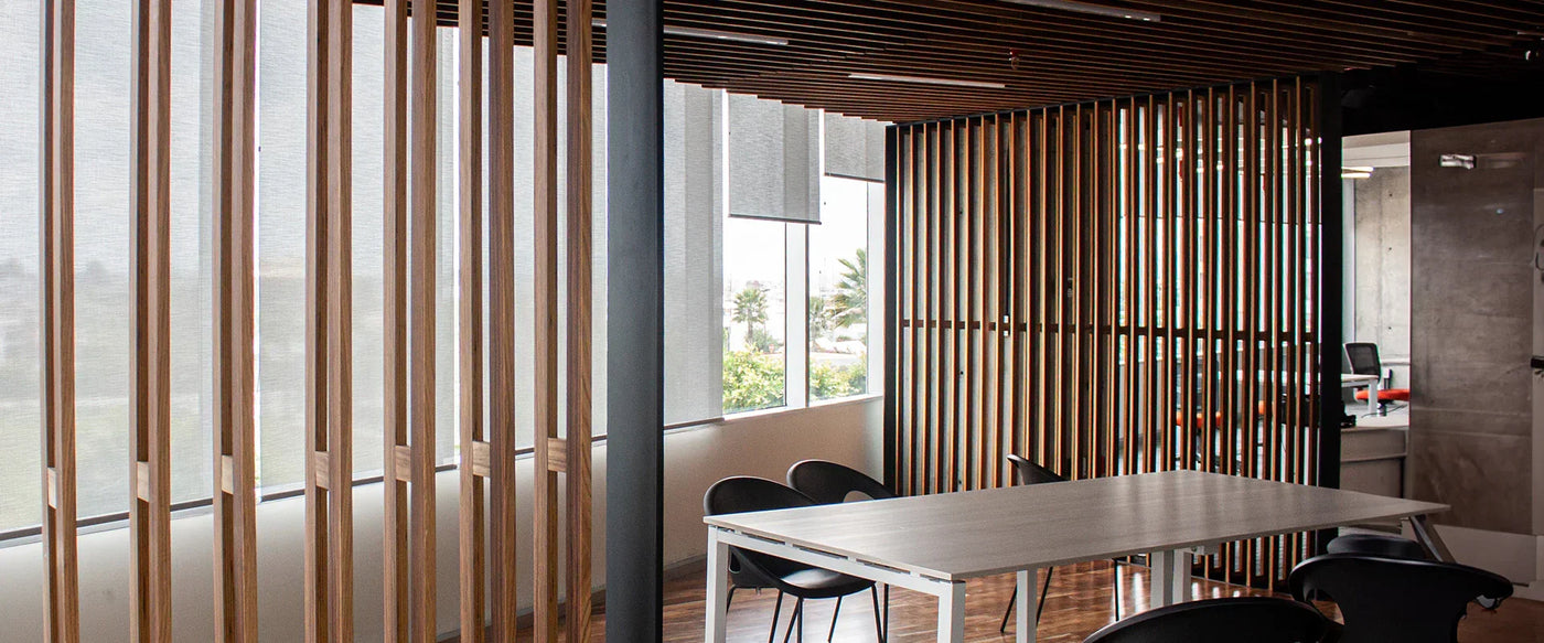 Modern office interior featuring wooden slat partitions, large windows, and a minimalist table with black chairs, creating an open atmosphere
