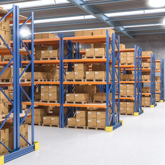 Brightly lit warehouse with blue and orange shelving units filled with neatly stacked cardboard boxes, showcasing organized storage space