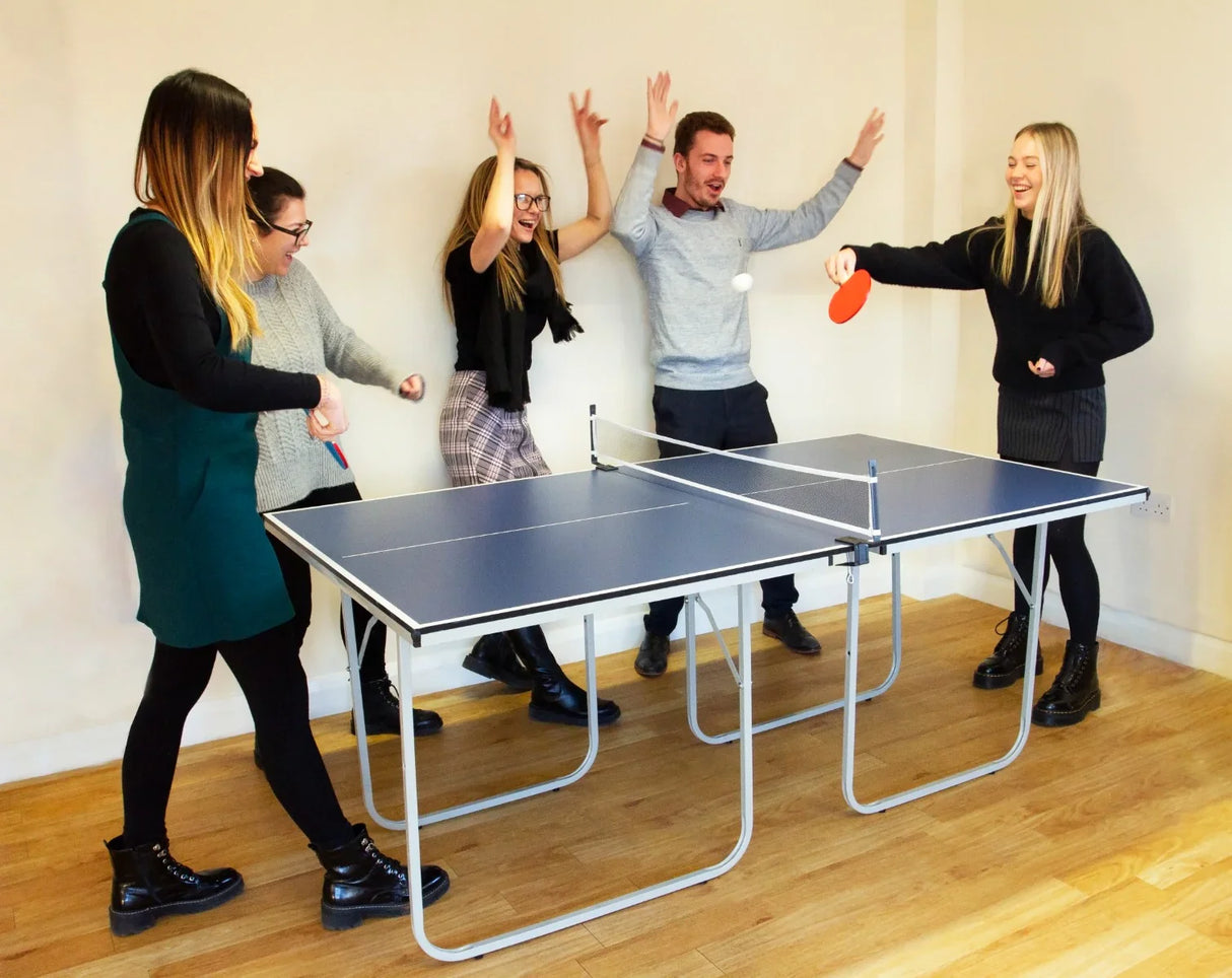 Folding table tennis table with a blue surface, surrounded by five people enjoying a game, showcasing fun and excitement