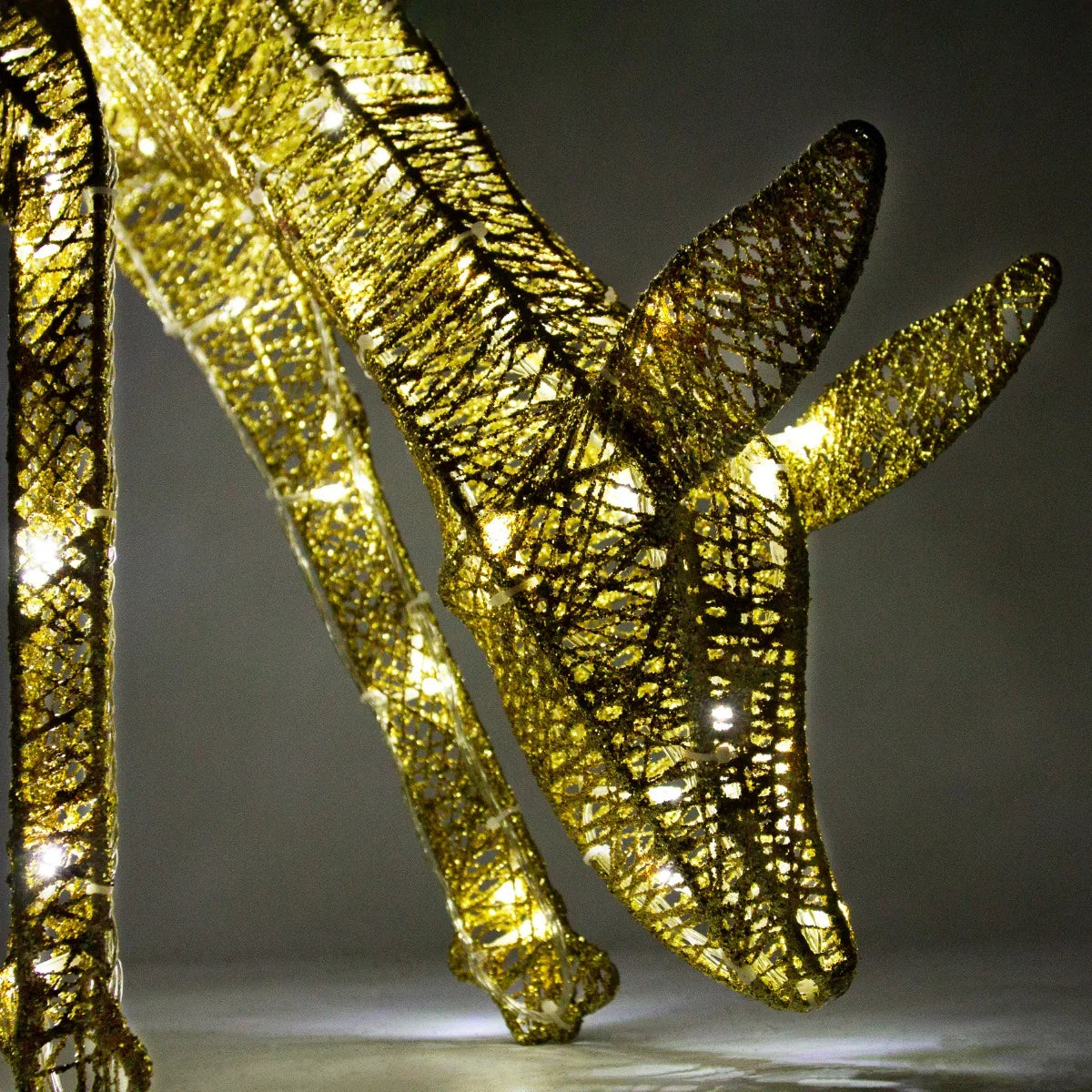 Gold stag and doe set with intricate wire design, illuminated by warm white lights, showcasing elegant shapes and textures