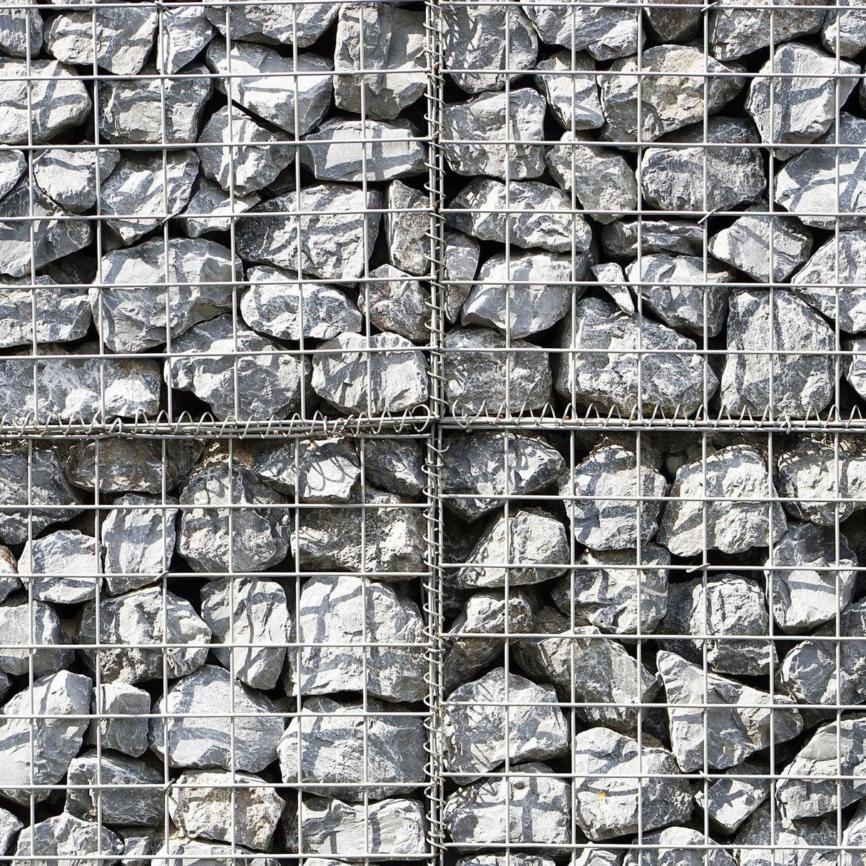 Gabion baskets filled with gray rocks, featuring a sturdy wire mesh structure, ideal for landscaping and erosion control projects