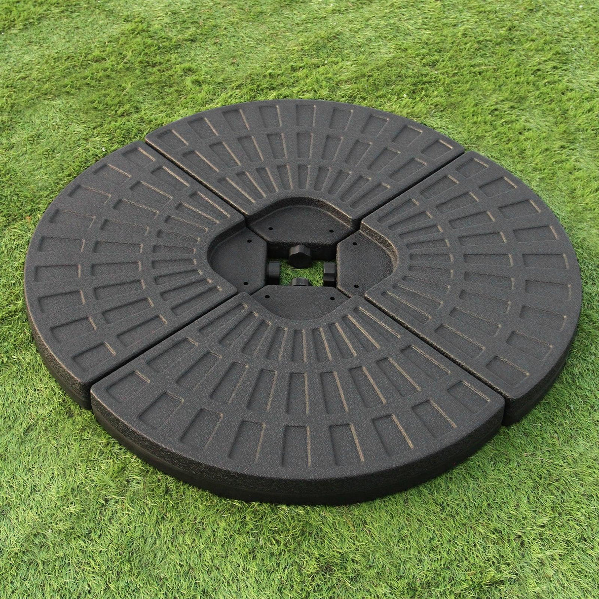 Round black fan base for a green cantilever parasol, featuring a textured surface and segmented design for stability on grass