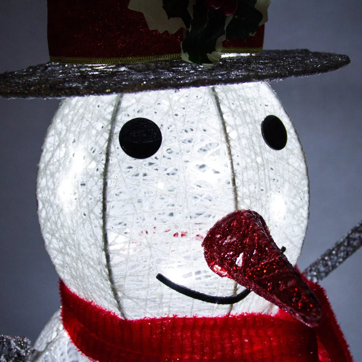 Light up snowman with a red scarf, black eyes, and a festive hat adorned with holly, showcasing a textured, illuminated design