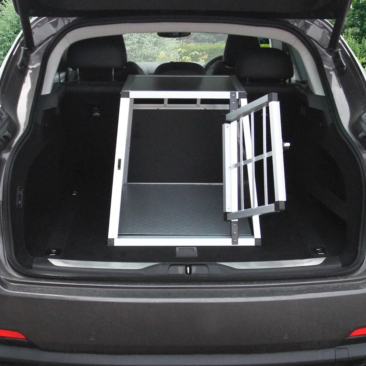 Large single door car dog crate in a spacious vehicle trunk, featuring a sturdy metal frame and textured black floor for durability