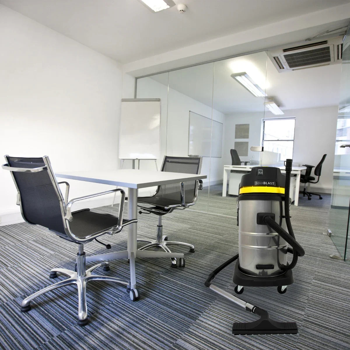 MAXBLAST 60L Industrial Vacuum Cleaner in a modern office setting, featuring a sleek silver body, black hose, and yellow accents