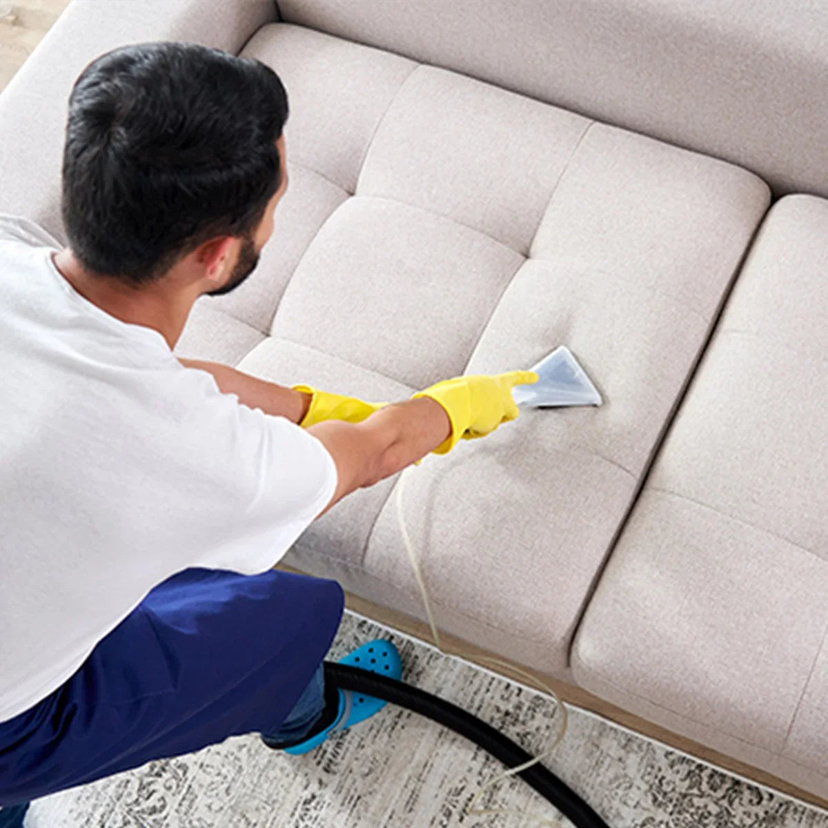 MAXBLAST Wet and Dry Vacuum Cleaner in use, cleaning a light beige fabric sofa with a gray nozzle, showcasing its effectiveness