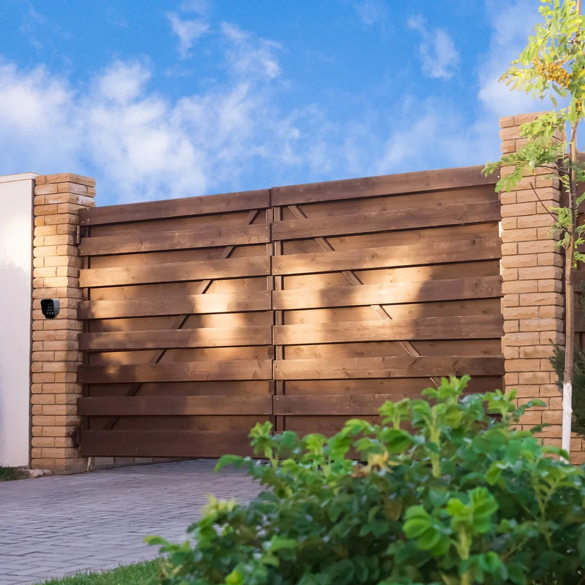 T-Mech Swing Gate Opener with wireless keypad on a stylish wooden gate, surrounded by greenery and a clear blue sky