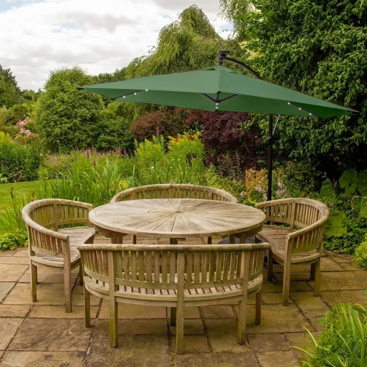 Green 3m LED cantilever parasol with a plain base, providing shade over a wooden circular table and curved benches in a garden setting