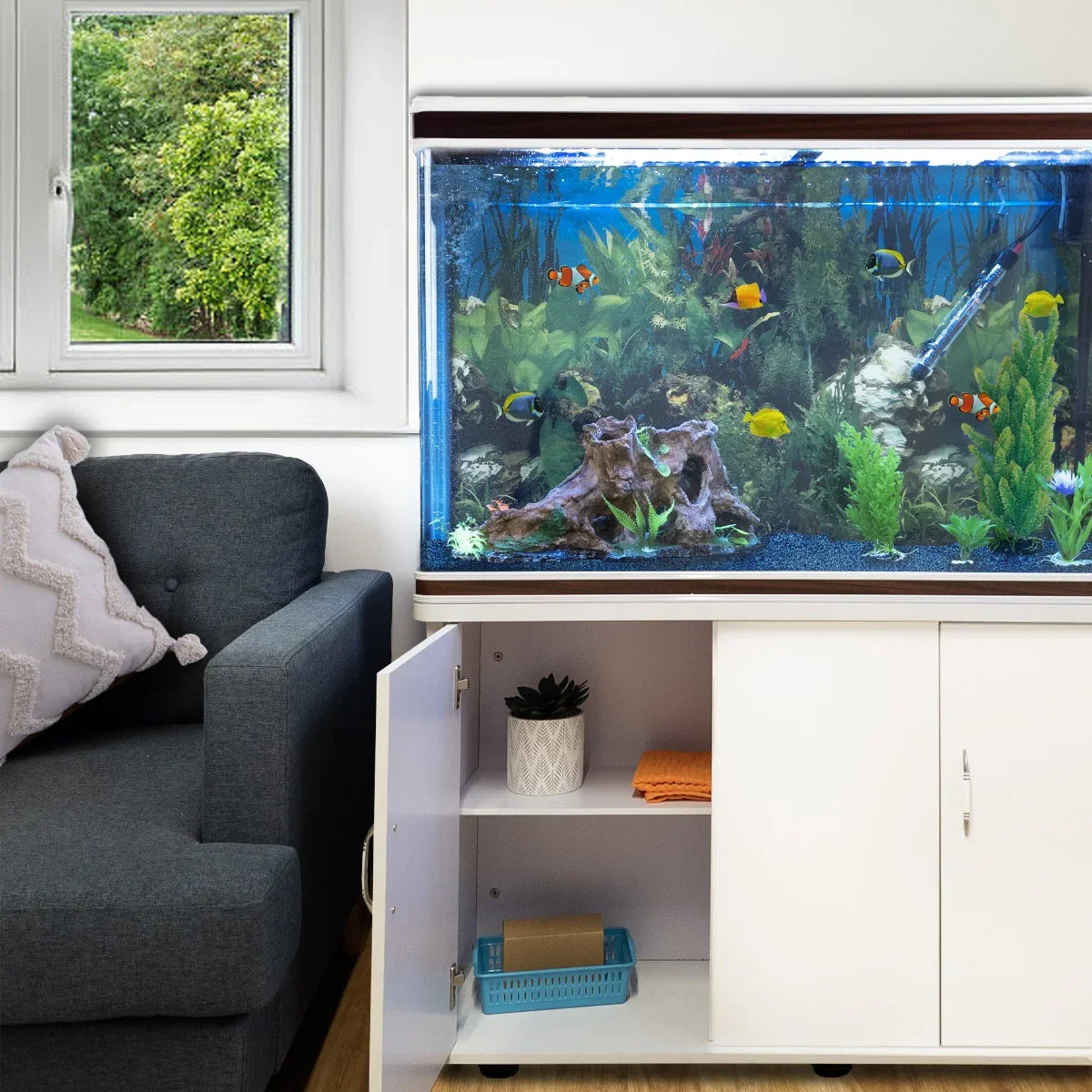 White aquarium fish tank with blue gravel, vibrant fish, and aquatic plants, paired with a sleek cabinet in a cozy living room setting