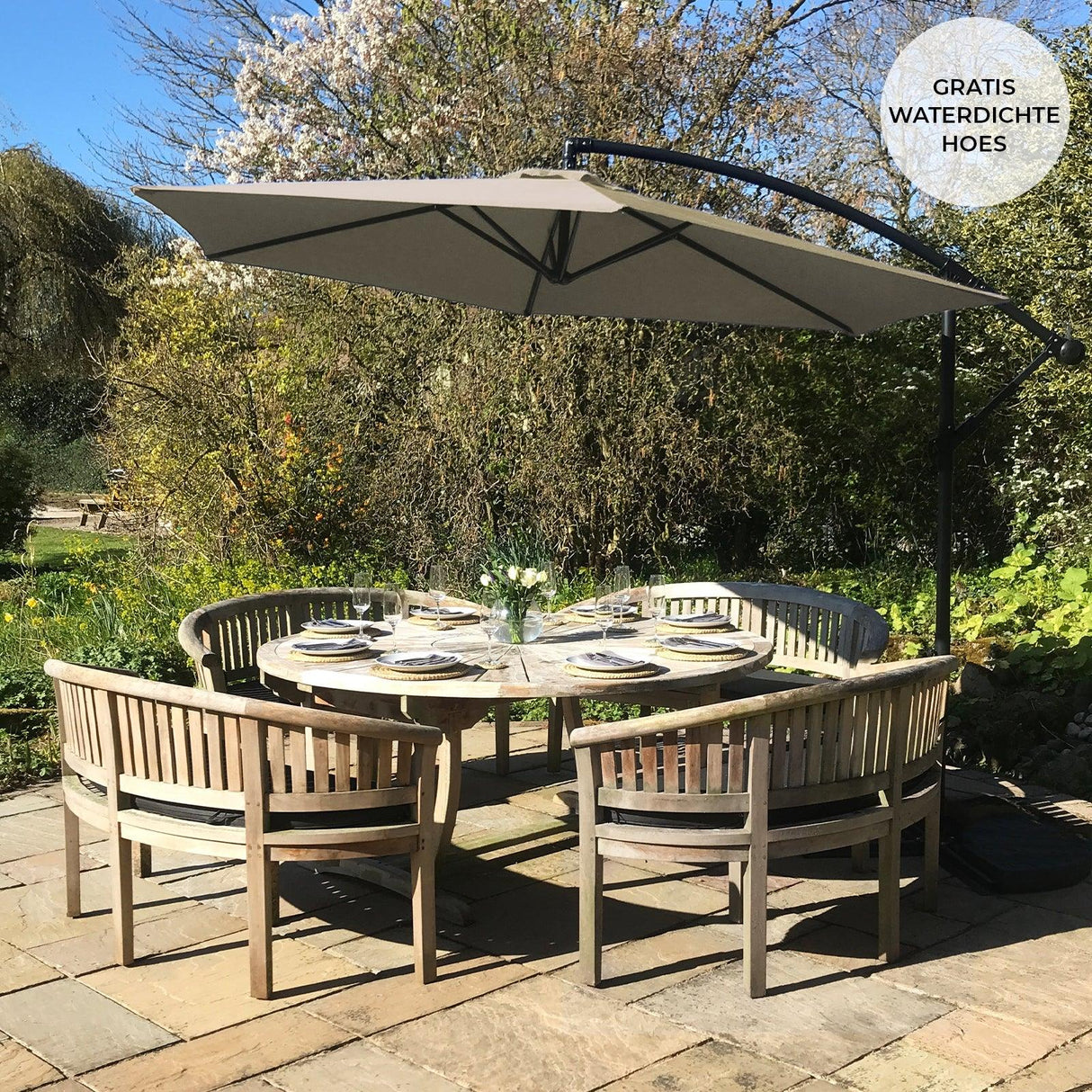 Beige cantilever parasol with a curved arm, providing shade over a round wooden dining table set in a garden with greenery