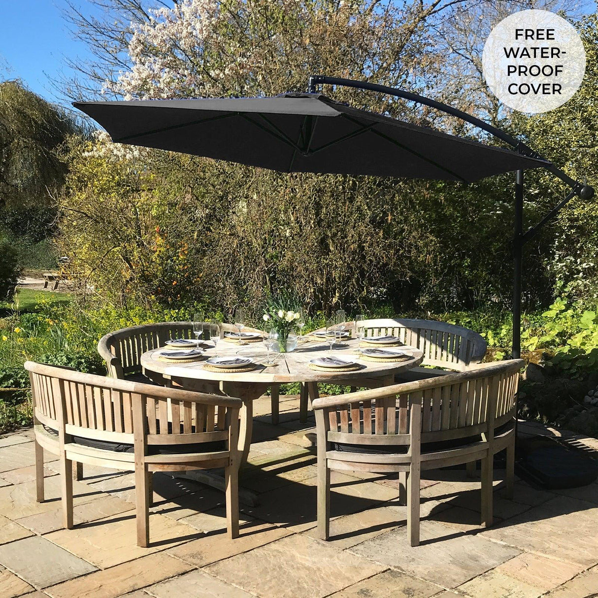 Black cantilever parasol with a sleek design, providing shade over a round wooden dining table set in a lush garden setting