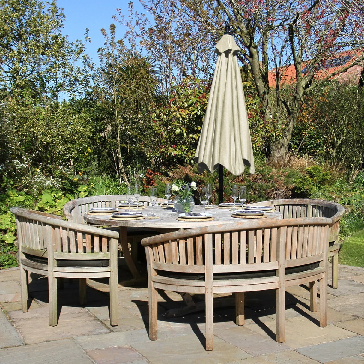 Cream cantilever parasol in a light beige color, shading a round wooden dining table surrounded by curved wooden chairs in a garden setting