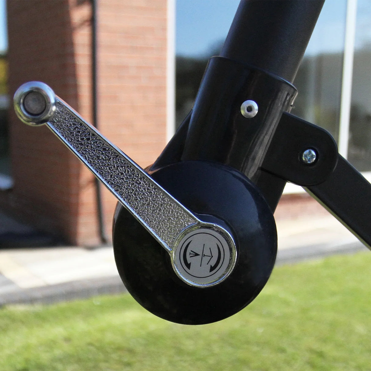 Close-up of the cream cantilever parasol's adjustable crank mechanism, showcasing a sleek black handle and textured silver accents
