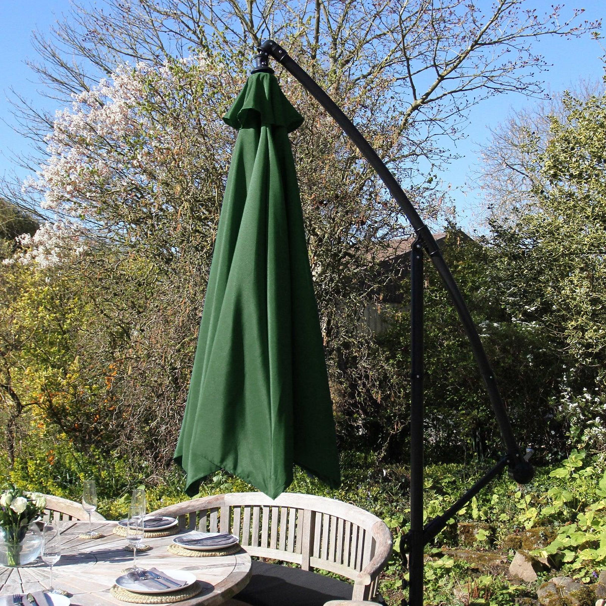 Green cantilever parasol with a sleek black frame and vibrant green fabric, providing shade over a wooden outdoor dining table