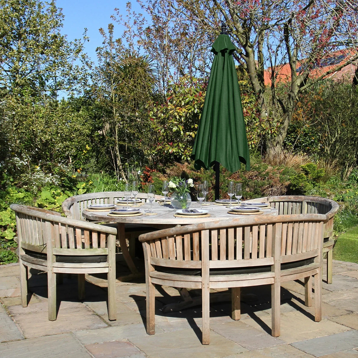 Green cantilever parasol stands tall over a rustic wooden dining set in a lush garden, providing shade and style for outdoor gatherings
