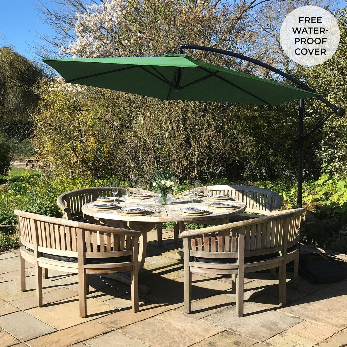 Green cantilever parasol with a large canopy, providing shade over a round wooden dining table set in a garden, surrounded by greenery
