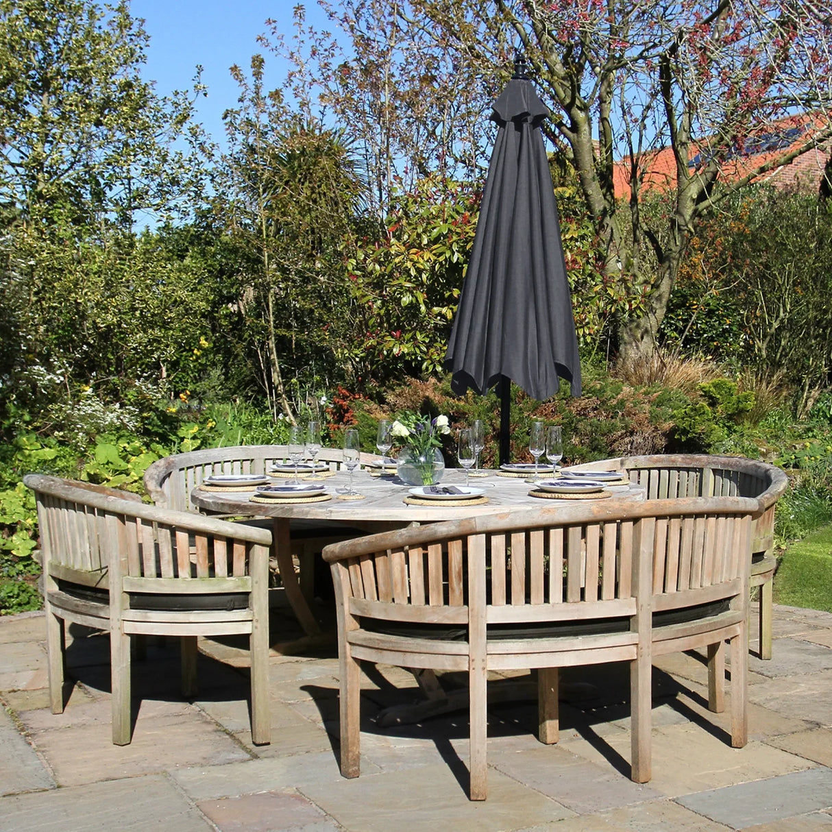 Grey cantilever parasol with a sleek design, standing above a rustic wooden dining set in a lush garden setting
