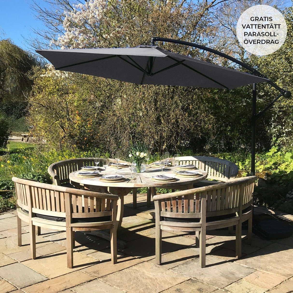 Grey cantilever parasol with a sleek design, providing shade over a round wooden dining table set in a lush garden setting