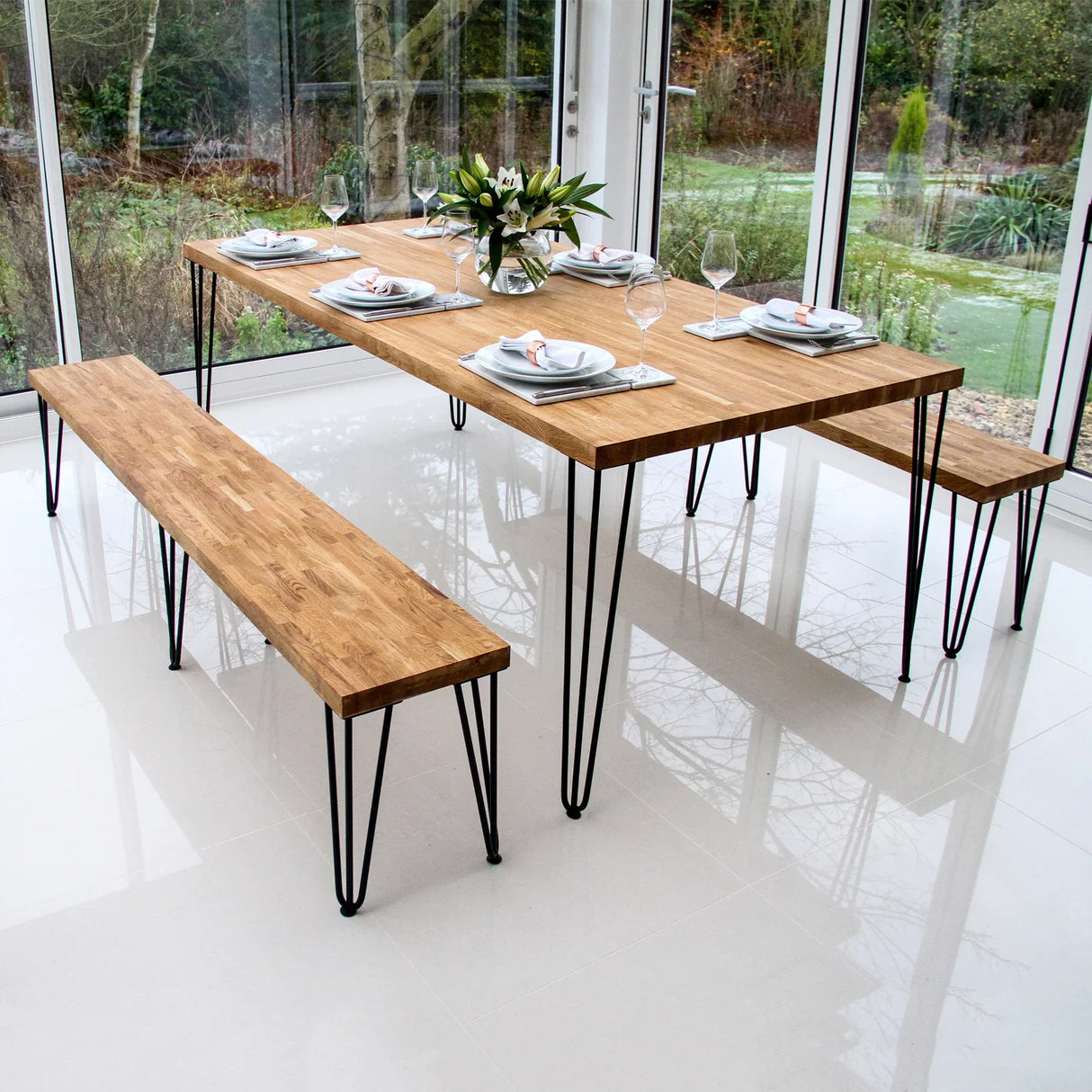 Black 12mm hairpin legs supporting a wooden dining table and benches, showcasing a modern, minimalist design in a bright setting