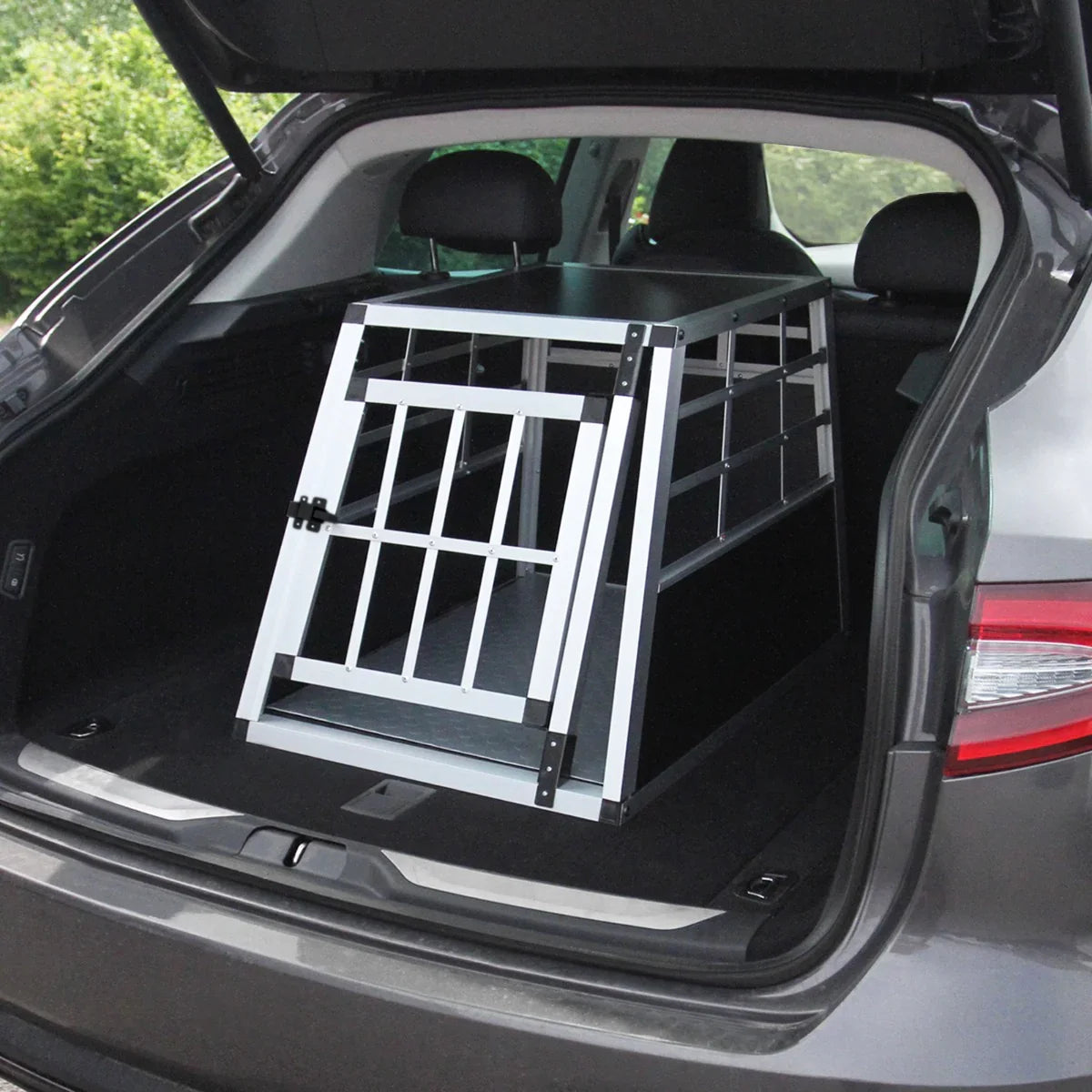 Small single door car dog crate in sleek aluminum design, fitted securely in the trunk of a vehicle, ideal for pet travel safety