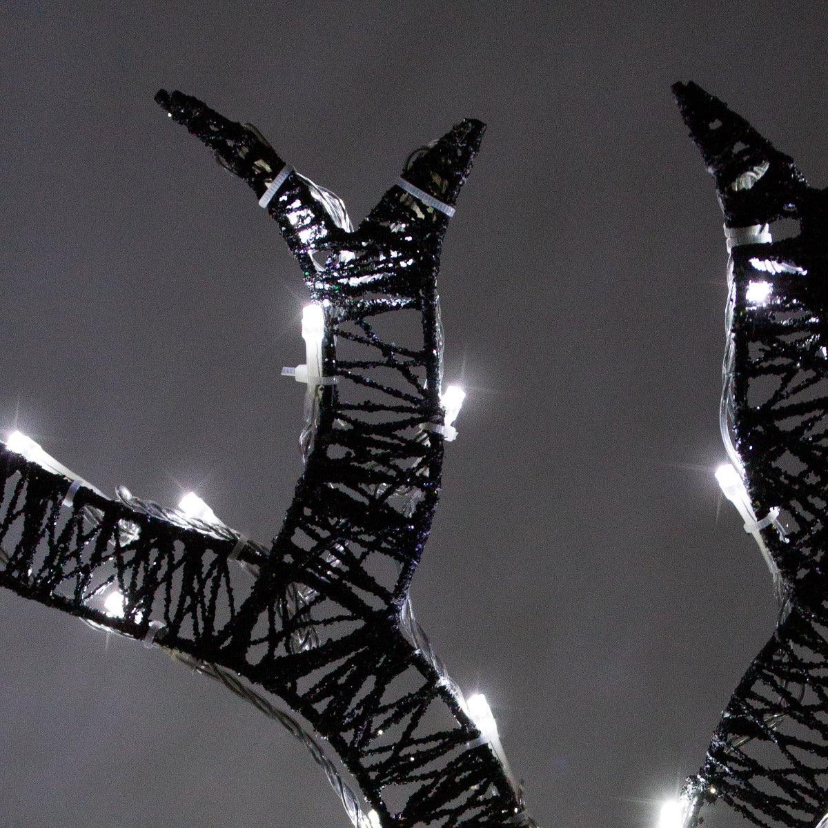 Glowing black wire antlers adorned with bright white lights, showcasing the elegant design of a reindeer decor set
