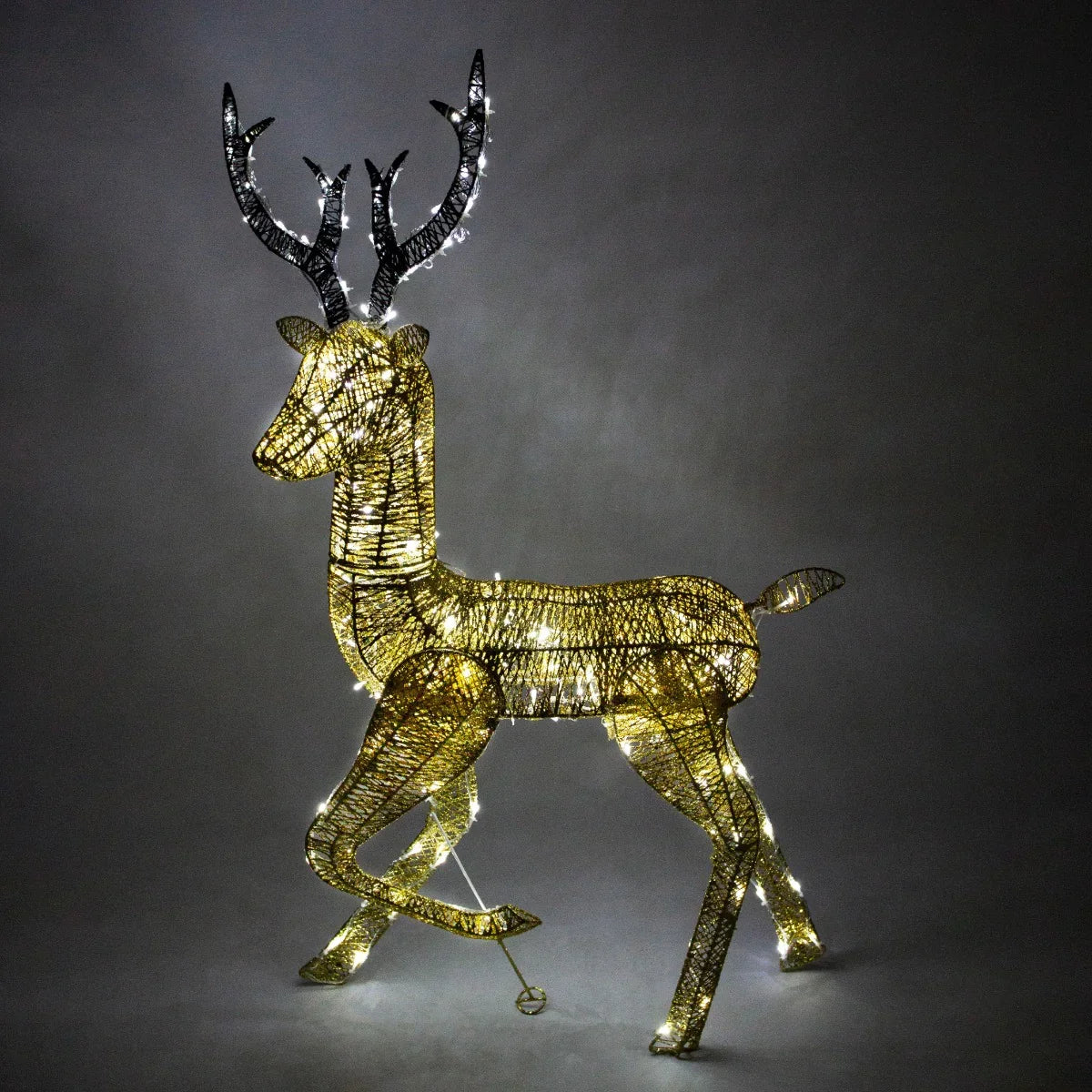 Gold stag reindeer sculpture with intricate wire design, illuminated with warm white lights, showcasing elegant antlers and a graceful pose