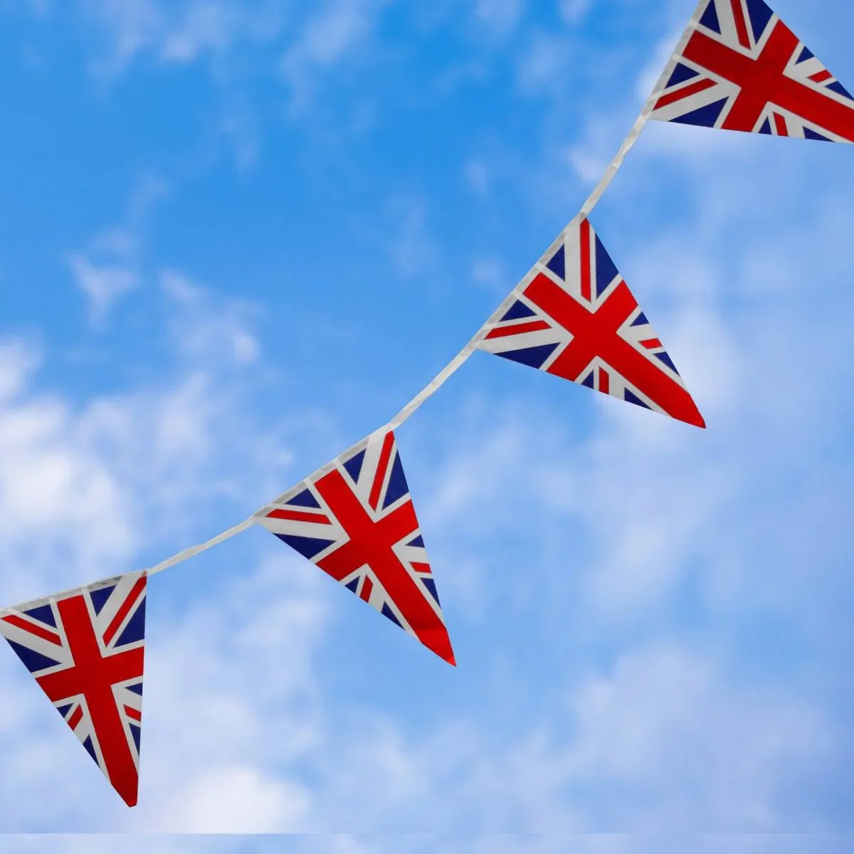 Union Jack flag bunting featuring vibrant red, white, and blue triangular flags strung against a bright blue sky