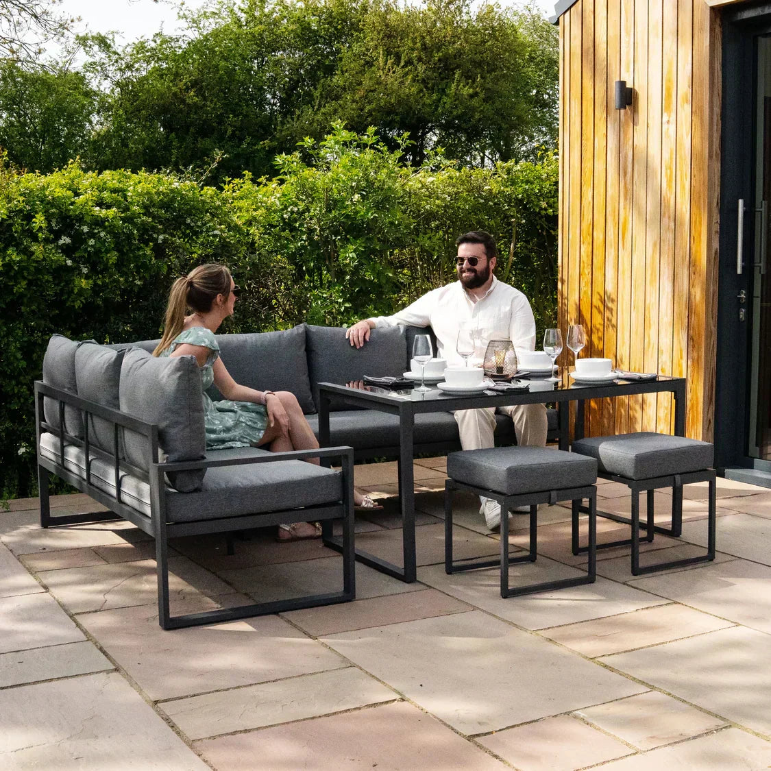 Stylish outdoor seating set with gray cushions, metal frames, and a matching table, perfect for summer gatherings in a garden setting