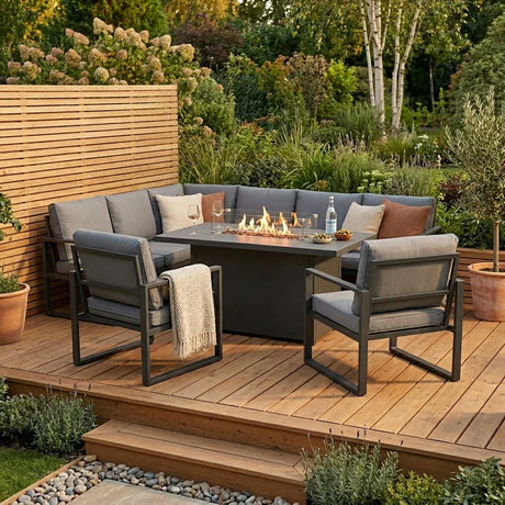Cozy outdoor seating area with gray cushions, a modern fire pit table, and lush greenery, perfect for extending outdoor gatherings