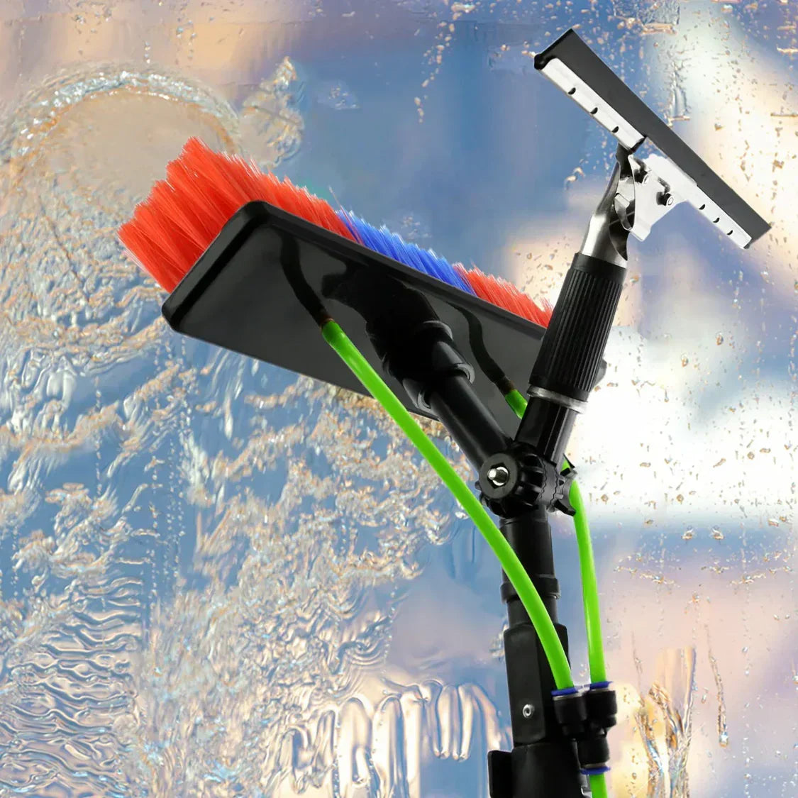 Multi-colored bristle cleaning brush with a squeegee attachment, designed for high-reach cleaning, set against a blurred glass background
