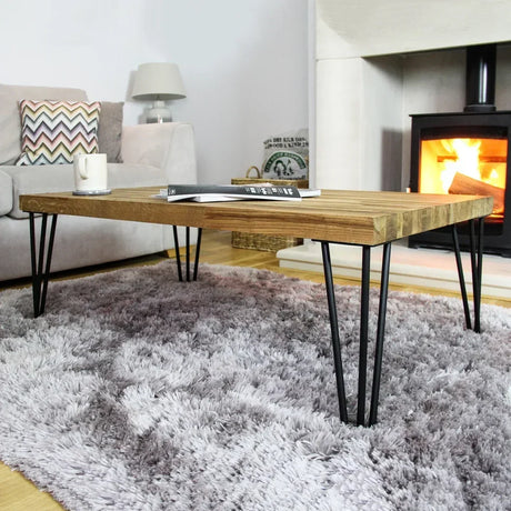 Stylish wooden coffee table with hairpin legs, set on a plush gray rug, near a cozy fireplace and a modern sofa