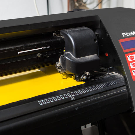 Vinyl cutting machine with a black body and red buttons, cutting a bright yellow sheet, showcasing precision and detail