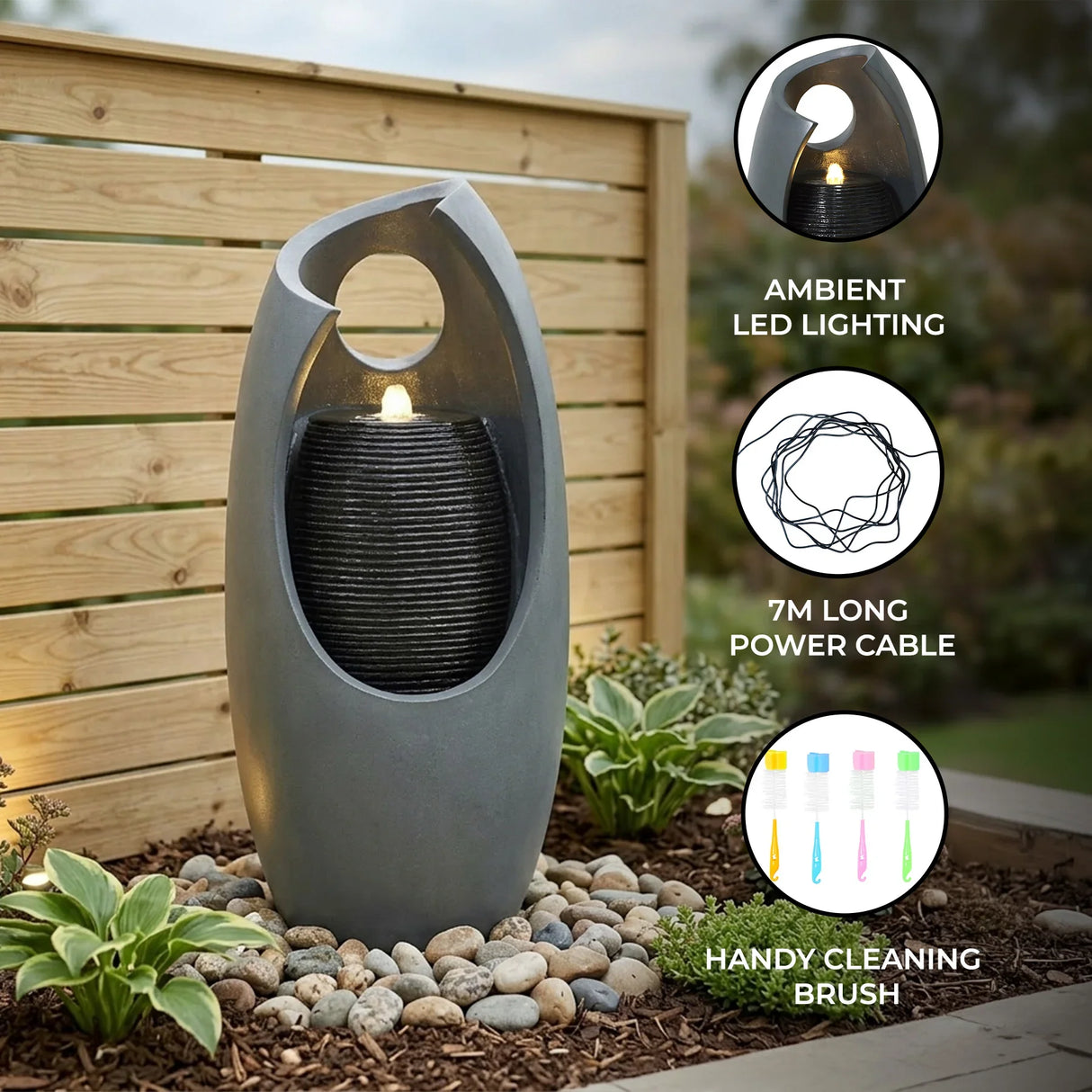 Sleek gray electric water feature with ambient LED lighting, cascading water, and a modern design, surrounded by decorative stones and plants