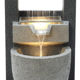 Elegant electric water feature with cascading water, textured gray stone finish, and soft glowing light illuminating the flow