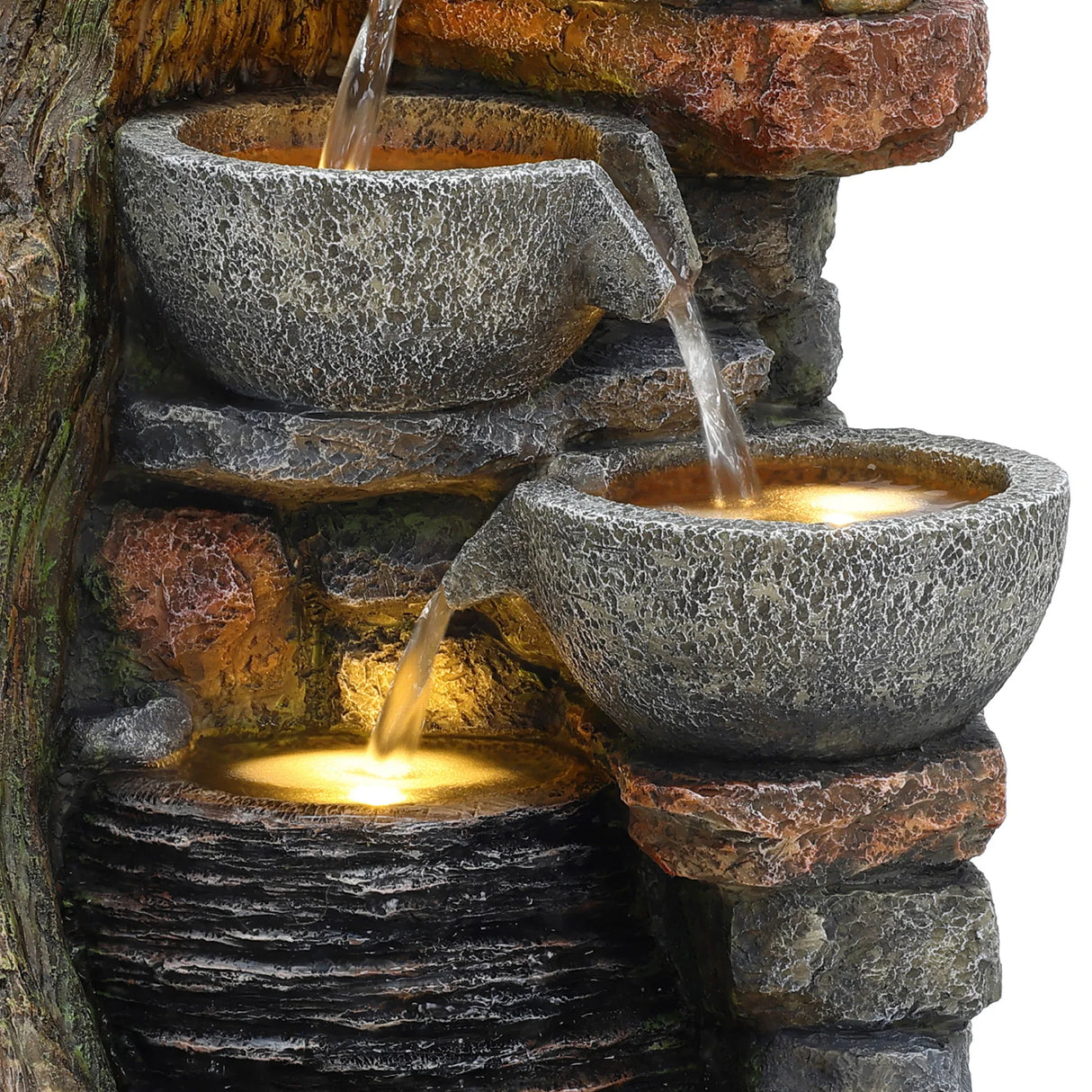 Rustic electric water feature with three textured stone bowls cascading water over a rocky surface, illuminated by soft lights