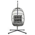 Grey rattan hanging egg chair with a plush, tufted cushion, suspended from a sturdy black metal frame, ideal for outdoor relaxation