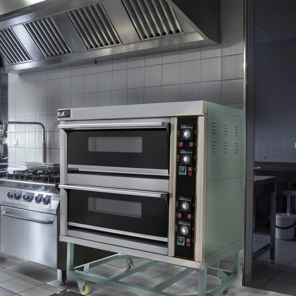 KuKoo large commercial pizza oven with two black baking chambers, stainless steel exterior, and control panel in a professional kitchen setting