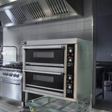 KuKoo large commercial pizza oven with two black baking chambers, stainless steel exterior, and control panel in a professional kitchen setting