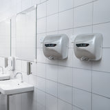 Sleek silver MAXBLAST hand dryers mounted on a tiled bathroom wall, reflecting light and enhancing modern restroom aesthetics