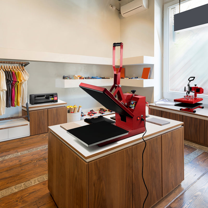 Bright red heat press machine on a wooden table in a modern shop, surrounded by colorful apparel and crafting tools