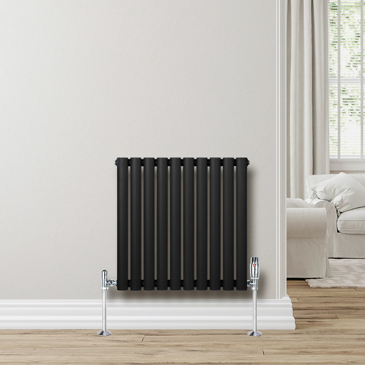Sleek black oval single column radiator with chrome valves, mounted on a light wall, enhancing modern interior decor