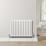 White oval single column radiator with chrome valves, 600mm x 780mm, mounted on a light-colored wall in a cozy living room setting