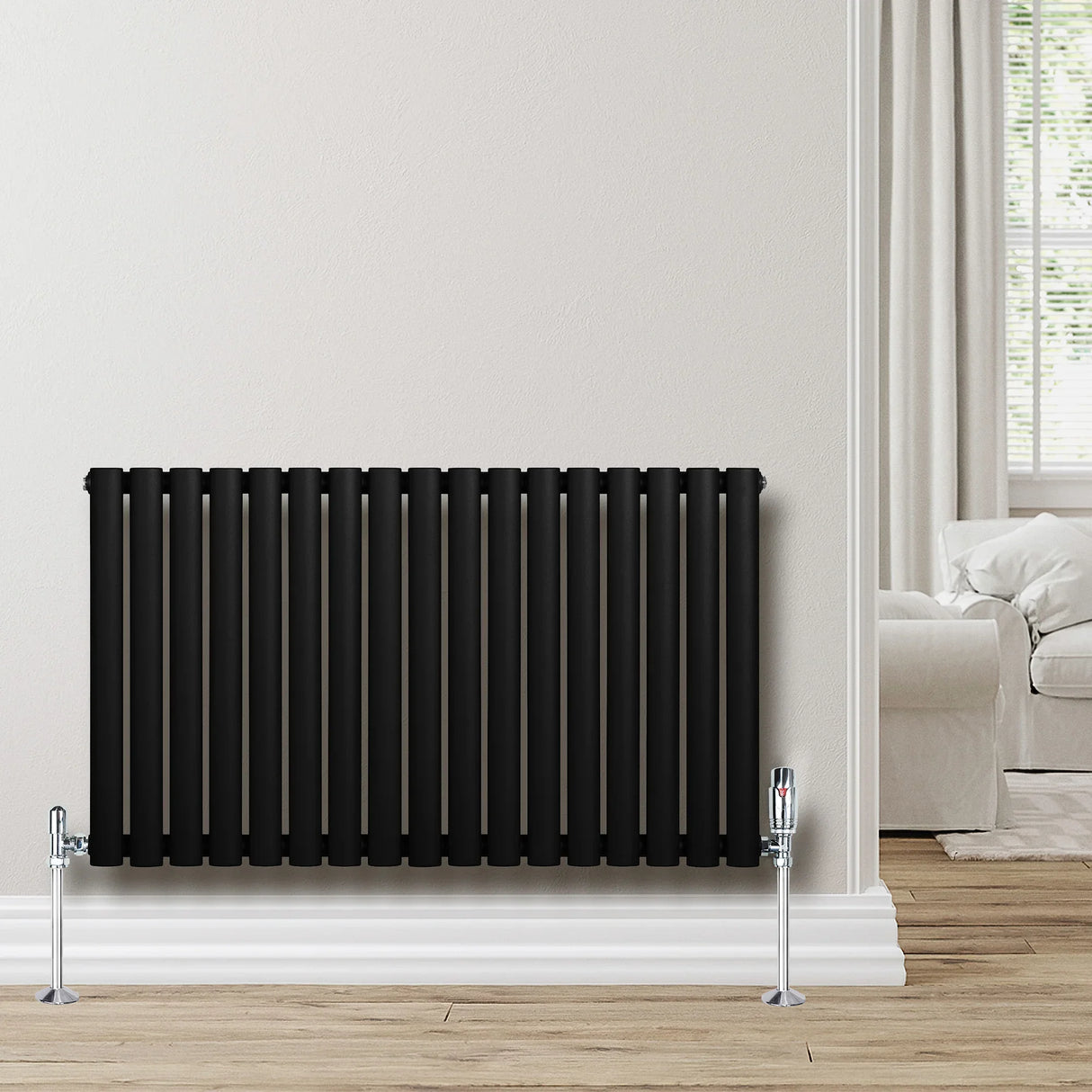 Sleek black oval single column radiator with chrome valves, mounted on a light wall, complementing a cozy living room setting