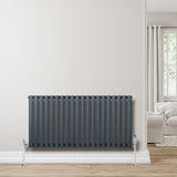 Oval single column radiator in anthracite grey, featuring sleek vertical tubes and chrome valves, mounted on a light wall