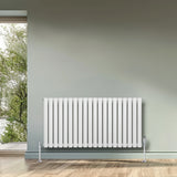 Oval single column radiator in white, 600mm x 1200mm, featuring sleek vertical lines and chrome valves, set against a light green wall
