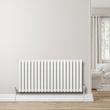 Sleek white oval single column radiator with chrome valves, 600mm x 1200mm, mounted on a light wall in a modern living space